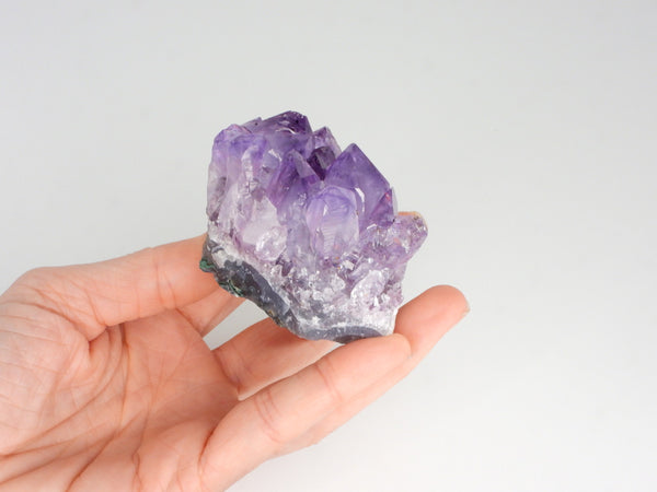 Beautiful Amethyst cluster with inclusions in someone's hand. Different angle