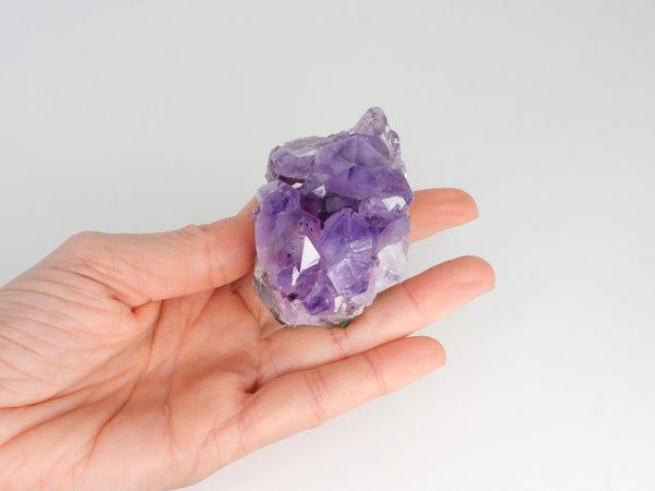 Beautiful Amethyst cluster with inclusions in someone's hand. Top view