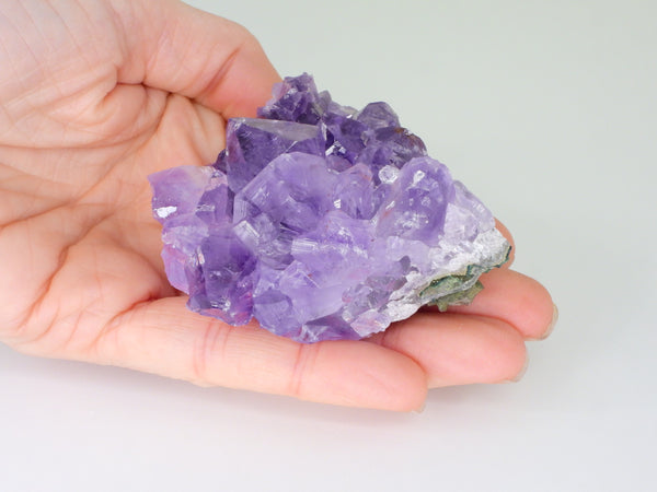 Beautiful Amethyst cluster with inclusions in someone's hand. Top view, angled