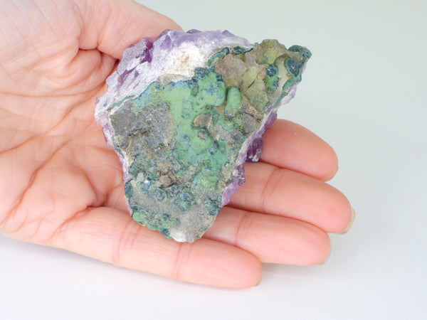 The bottom of a beautiful Amethyst cluster with inclusions in someone's hand. Bottom view