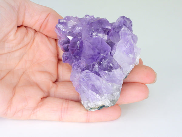 Beautiful Amethyst cluster with inclusions in someone's hand. Top view