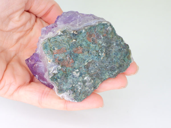 The bottom of a beautiful Amethyst cluster with inclusions in someone's hand. Bottom view