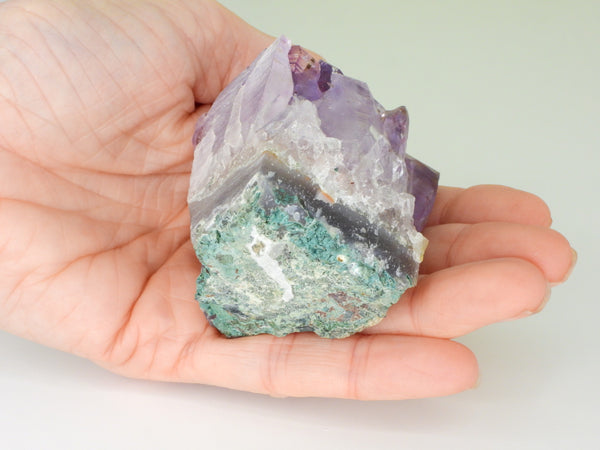 The bottom of a beautiful Amethyst cluster with inclusions in someone's hand. Bottom view