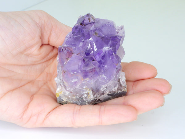 Beautiful Amethyst cluster with inclusions in someone's hand. Top view