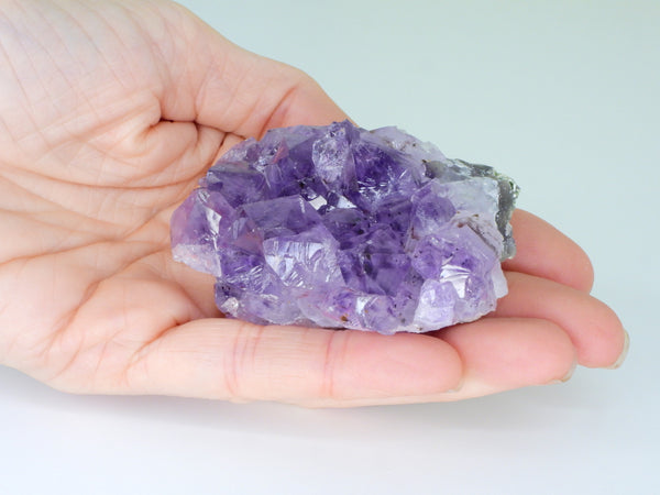 Beautiful Amethyst cluster with inclusions in someone's hand. Top view