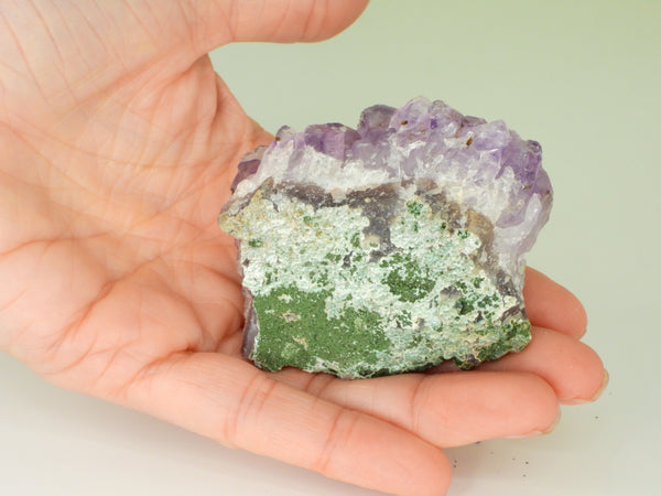 The bottom of a beautiful Amethyst cluster with inclusions in someone's hand. Bottom view