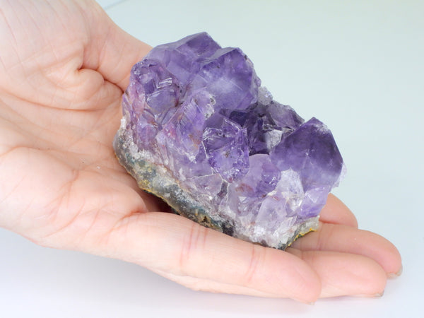 Beautiful Amethyst cluster with inclusions in someone's hand. Close up