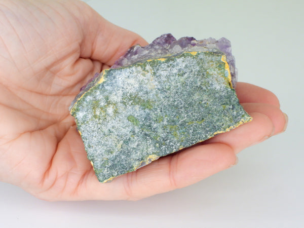 The bottom of a beautiful Amethyst cluster with inclusions in someone's hand. Bottom view