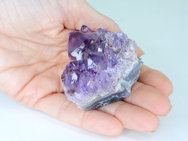 Beautiful Amethyst cluster with inclusions in someone's hand. Top view