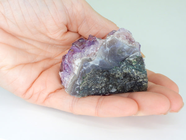 The bottom of a beautiful Amethyst cluster with inclusions in someone's hand. Bottom view