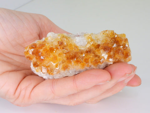 Beautiful Citrine cluster with inclusions in someone's hand. Top view