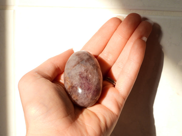 Purple Rose Quartz palm stone in someone's hand